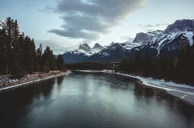 Stunning Canmore view with snow-capped peaks and a serene river—perfect for nature lovers.