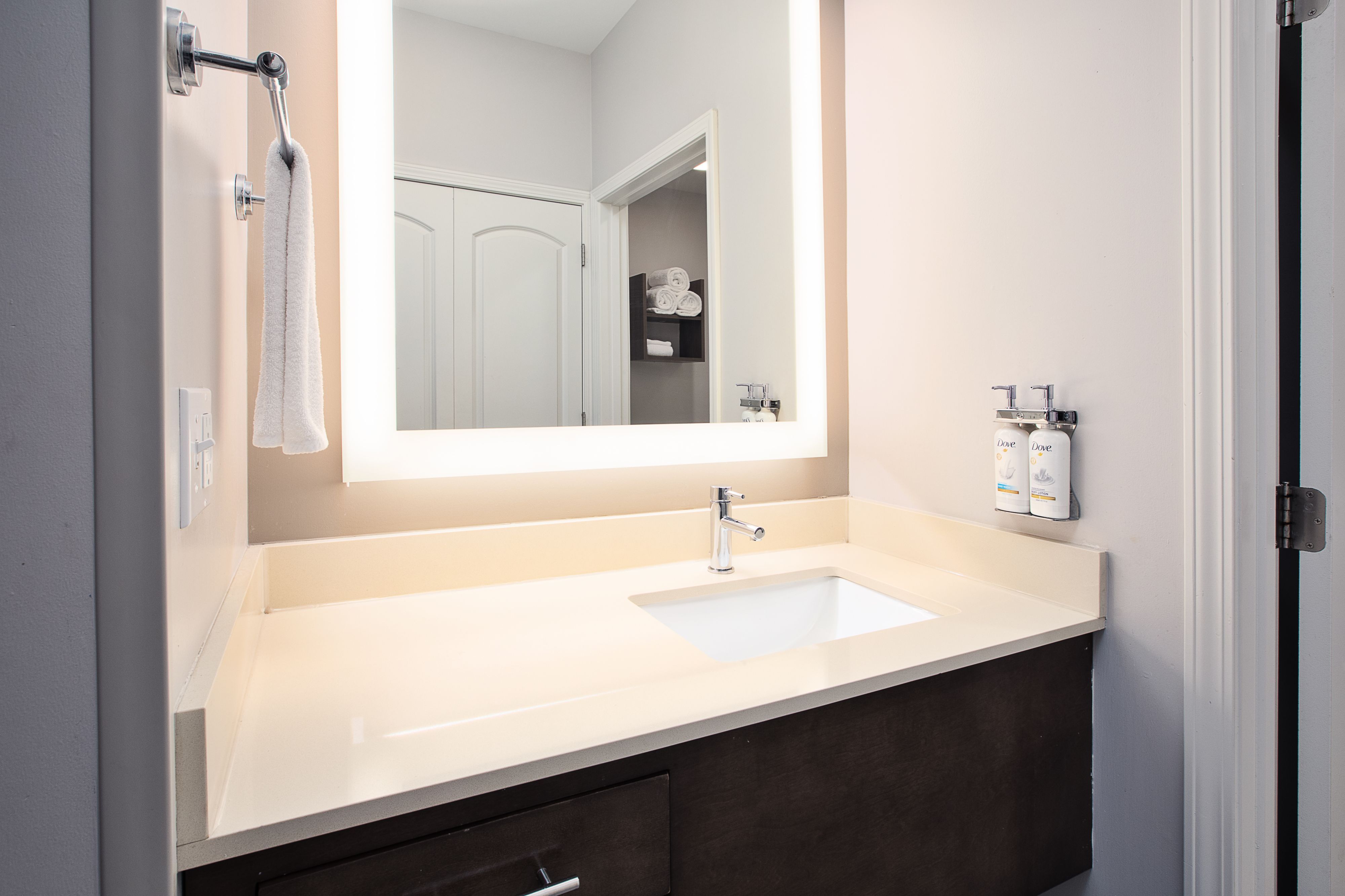 image Bathroom vanity with wall mirror, sink, and toiletries.