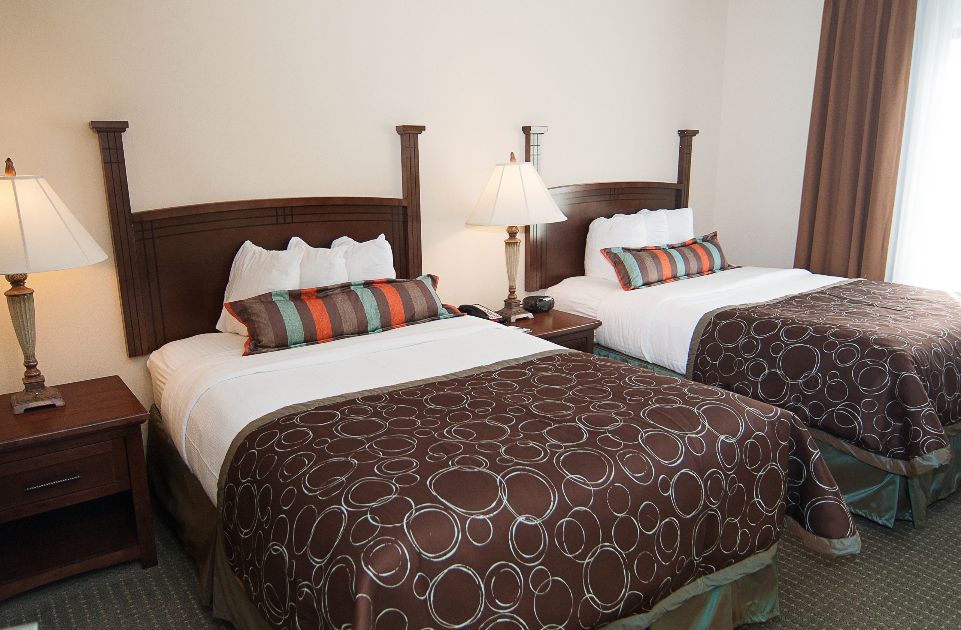 image Two beds with decorative pillows and bedside lamps.
