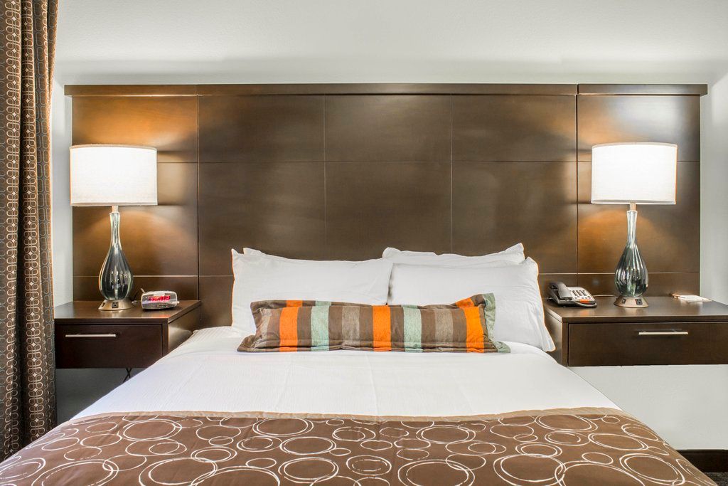 image Rest easy on the comfortable queen bed, accented with vibrant pillows and stylish lamps on either side for a warm ambiance.