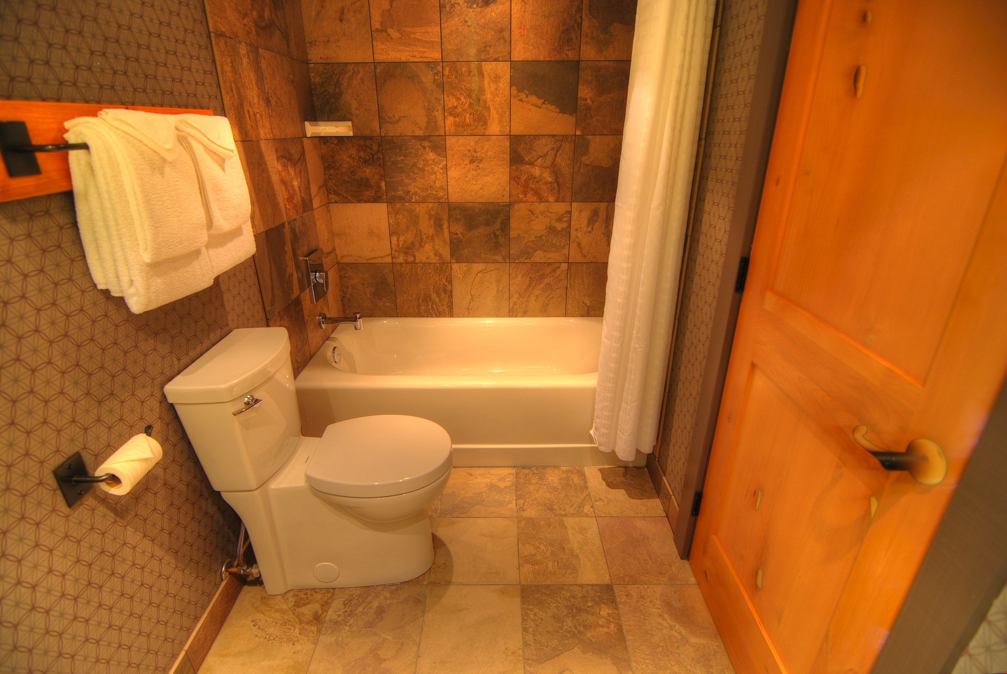 image The spacious bathroom features lovely wood and stone decor.