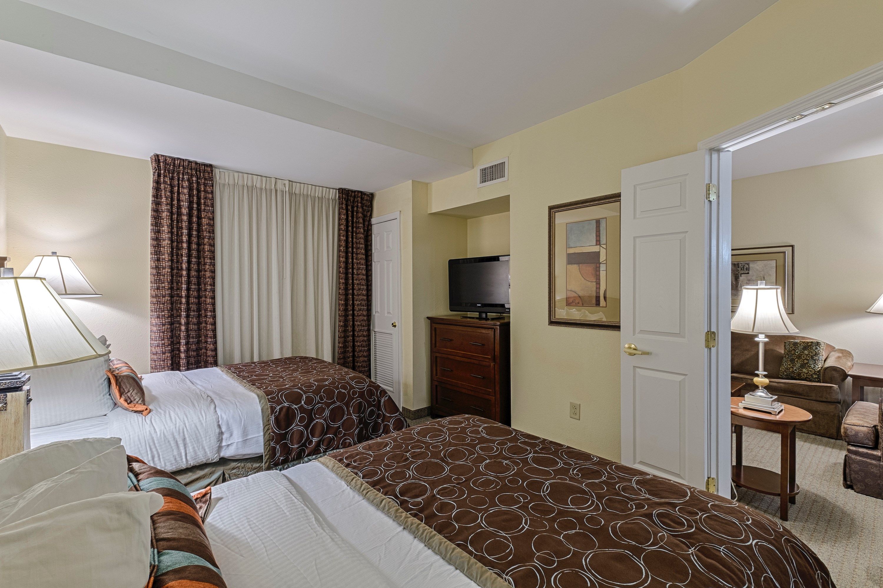 image Two double beds with a sofa seating area beyond, table lamps casting warm light across the room