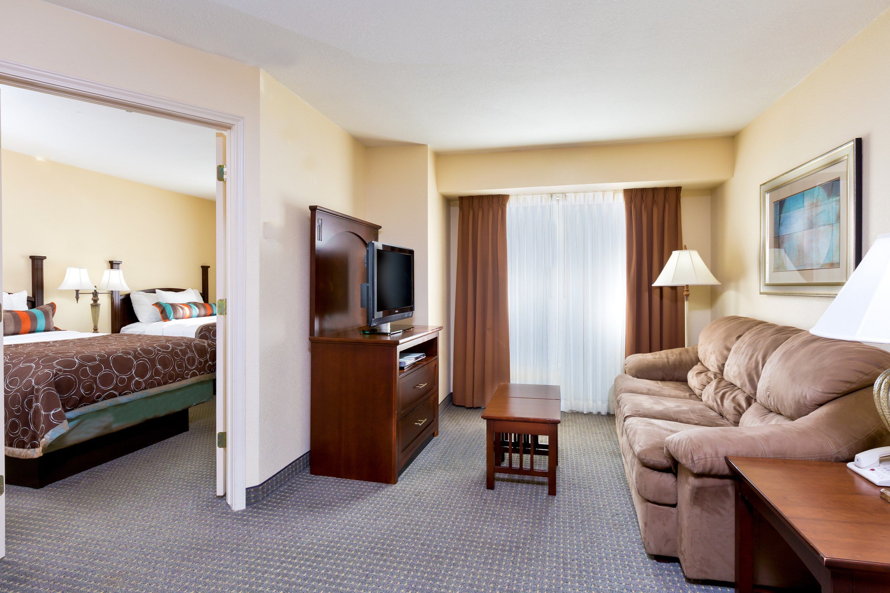 image Open-plan suite with two double beds, a living area with flatscreen TV, sofa, and coffee table — all in one light-filled space