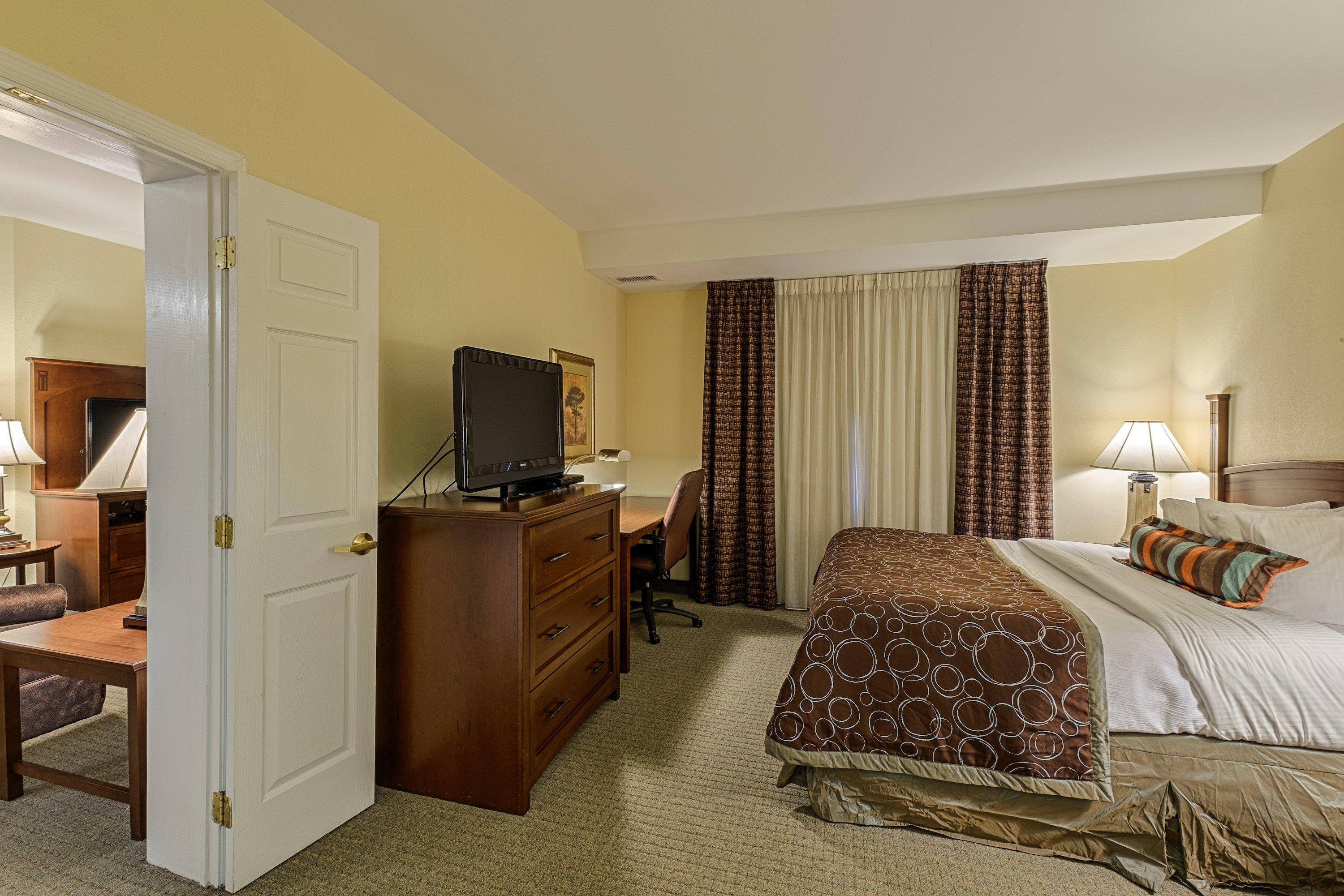 image Bedroom with a double bed, flatscreen TV, desk and chair, and a large window with curtains