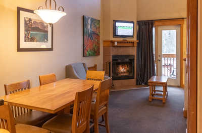 Enjoy meals at the spacious dining table or relax by the cozy fireplace in this warm and inviting living space.