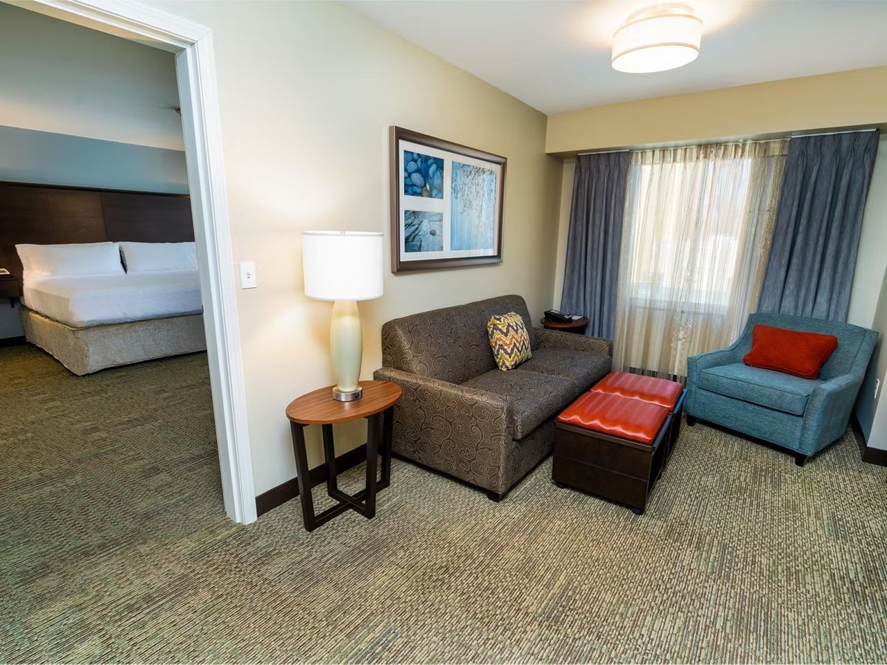 image Living area with a sofa bed, armchair, and light fixture near a window.