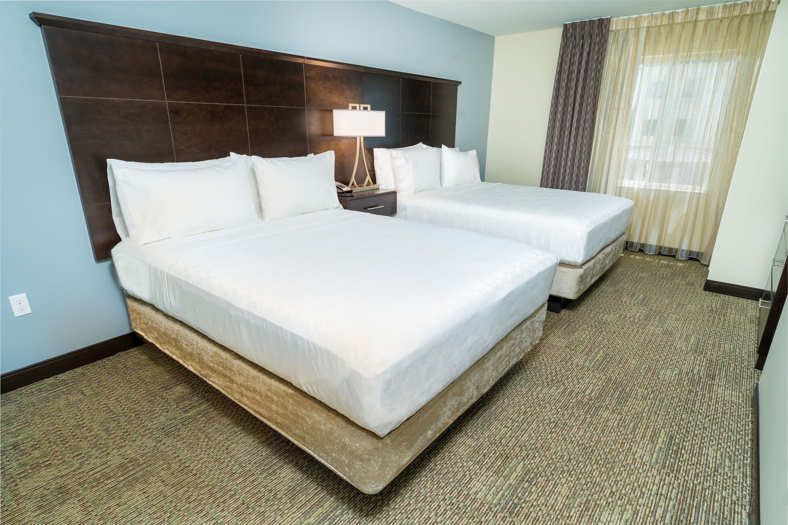 image Room with two beds, bedside lamps, and curtains letting in natural light.
