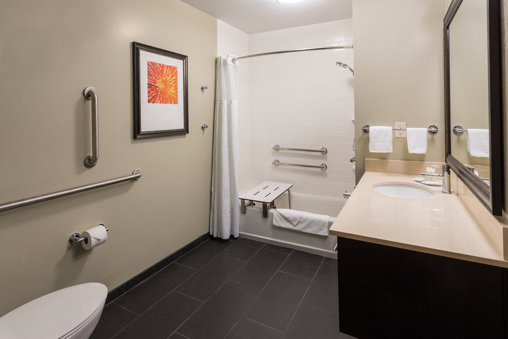 image Relax in the spacious bathroom featuring modern fixtures and a luxurious accessible bathtub.