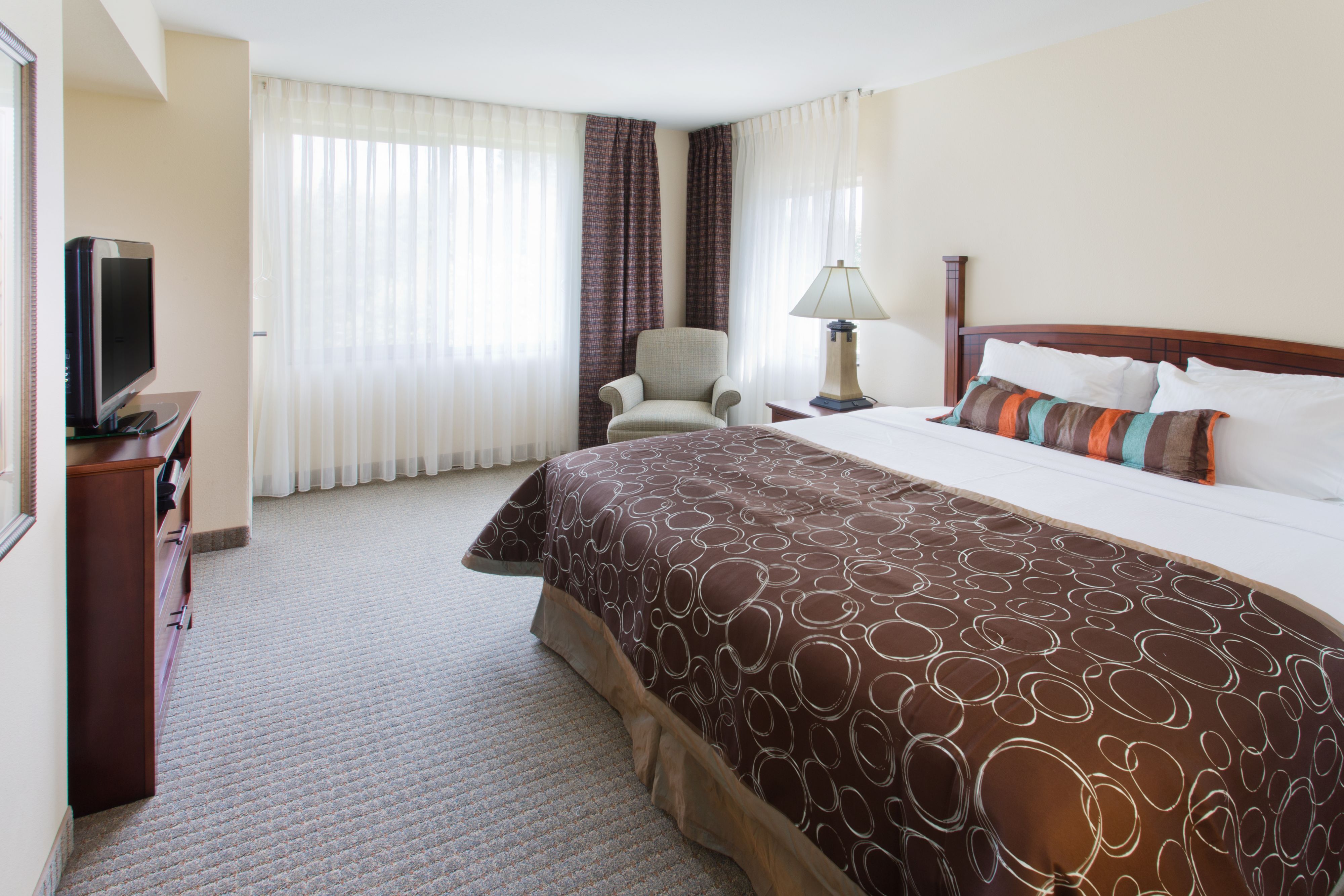 image Bright bedroom with a comfortable bed and armchair.