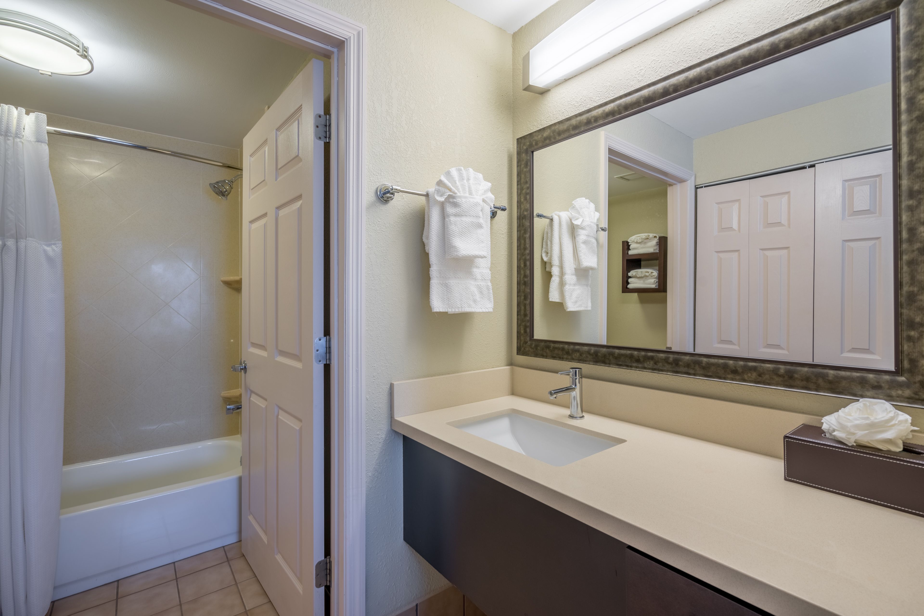 image Bathroom with full tub, shower curtain, and neatly folded towels.