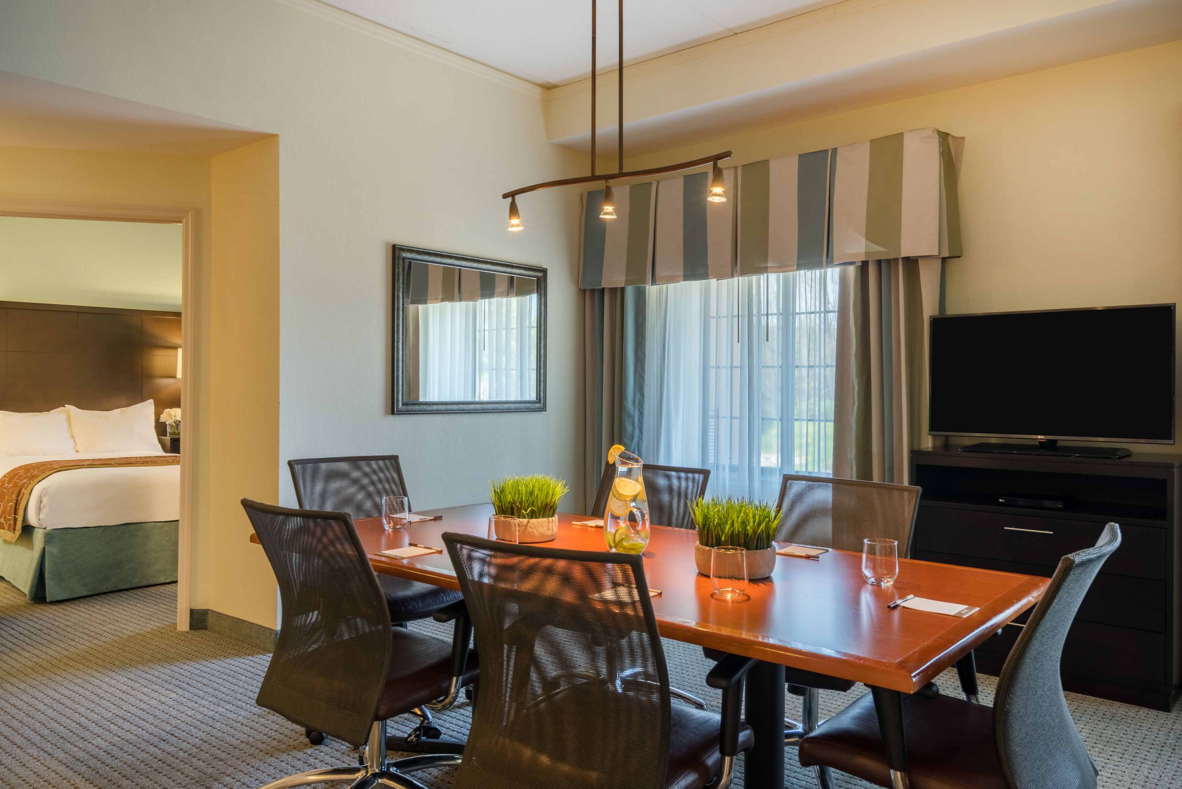 image Dining and conference area with a long table, cushioned chairs, and pendant lighting overhead.