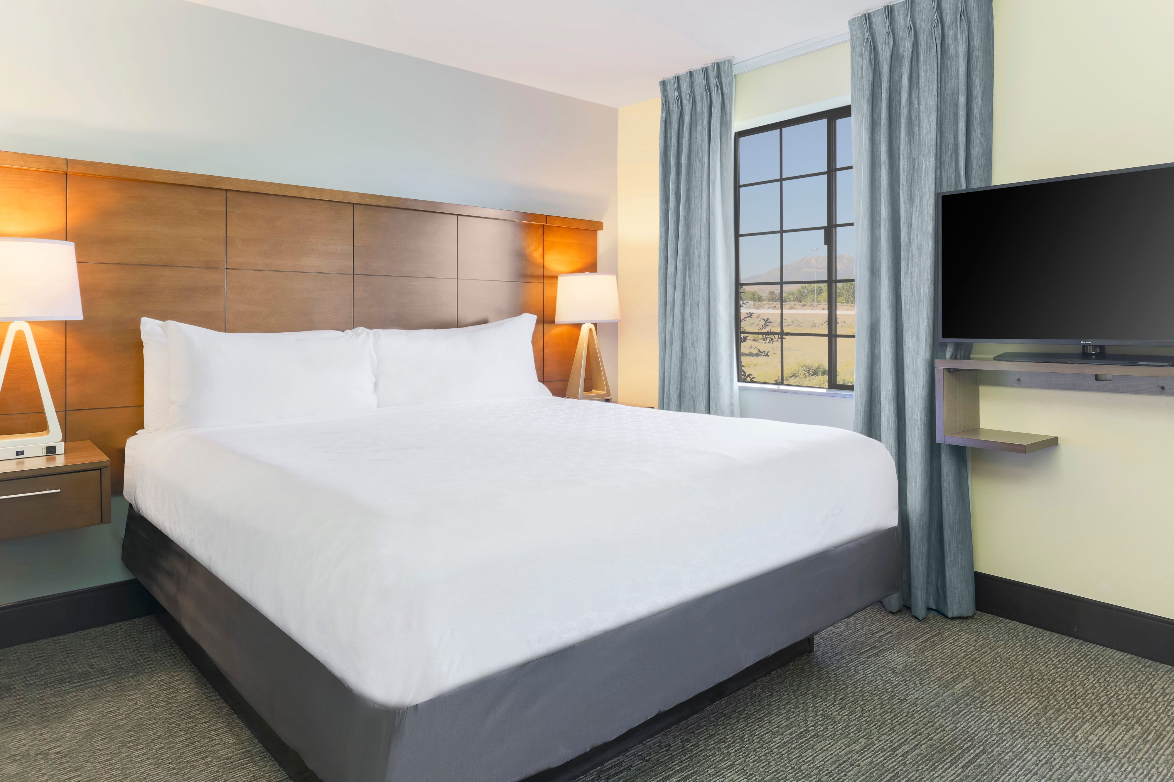 image Settle in with the king bed and flat-screen TV in a warm, wood-paneled setting.