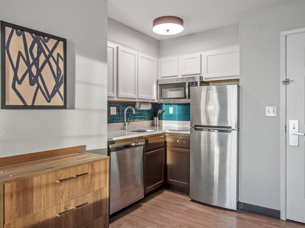 image A well-equipped kitchen with stainless steel appliances, white cabinetry, and a tile backsplash.