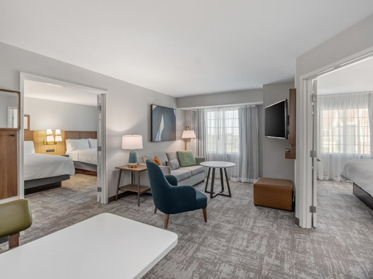 image A shared living area with a sofa and armchair, positioned between two separate bedrooms.
