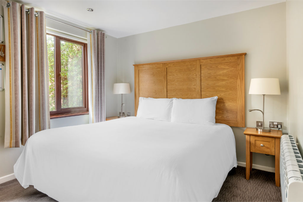 image Serene bedroom retreat with plush bedding and warm wood finishes.