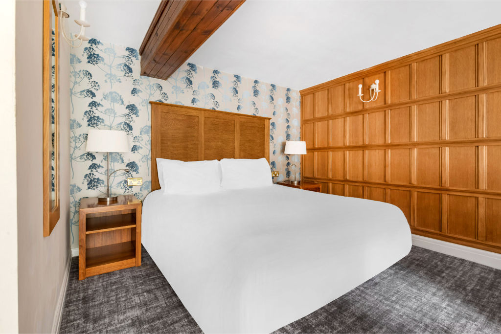 image Unique corner bedroom with a wood-paneled wall and cozy ambiance.