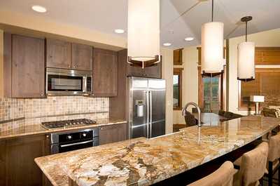 The fully-equipped kitchen features granite countertops, stainless steel appliances and a breakfast bar