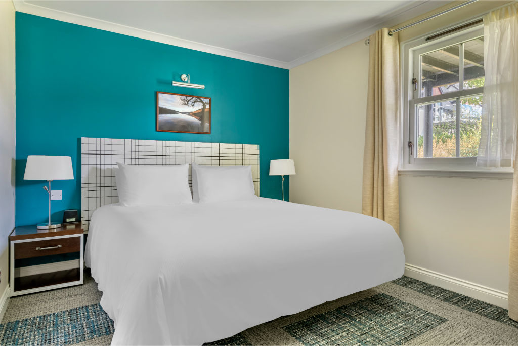 image Bedroom featuring a striking accent wall and comfortable furnishings for a restful stay.