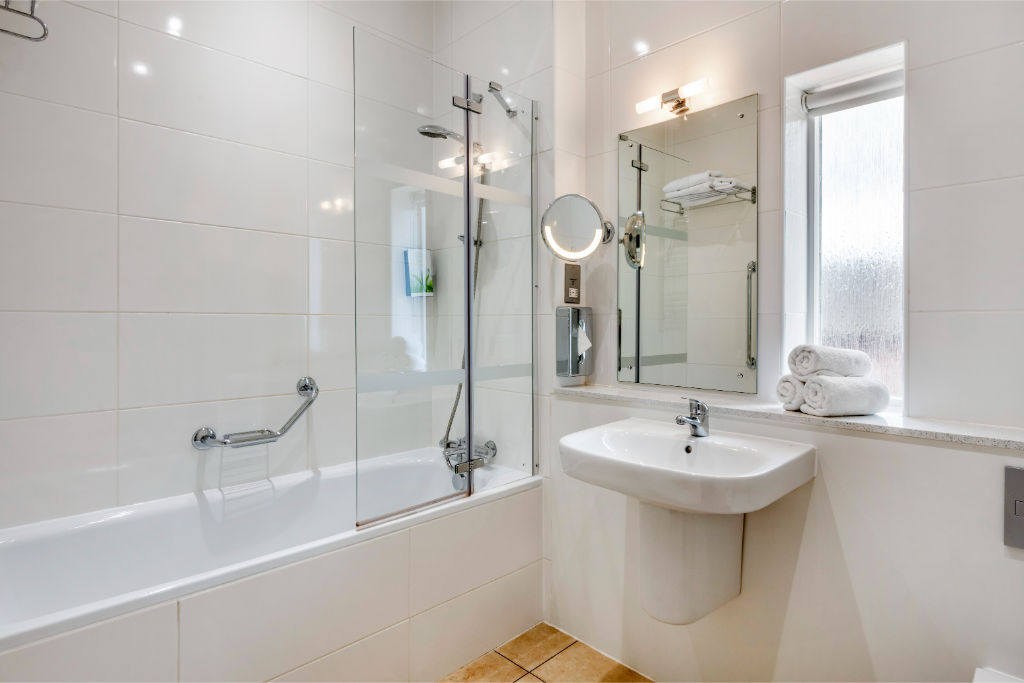 image A well-lit bathroom featuring clean lines and a combination tub and shower.