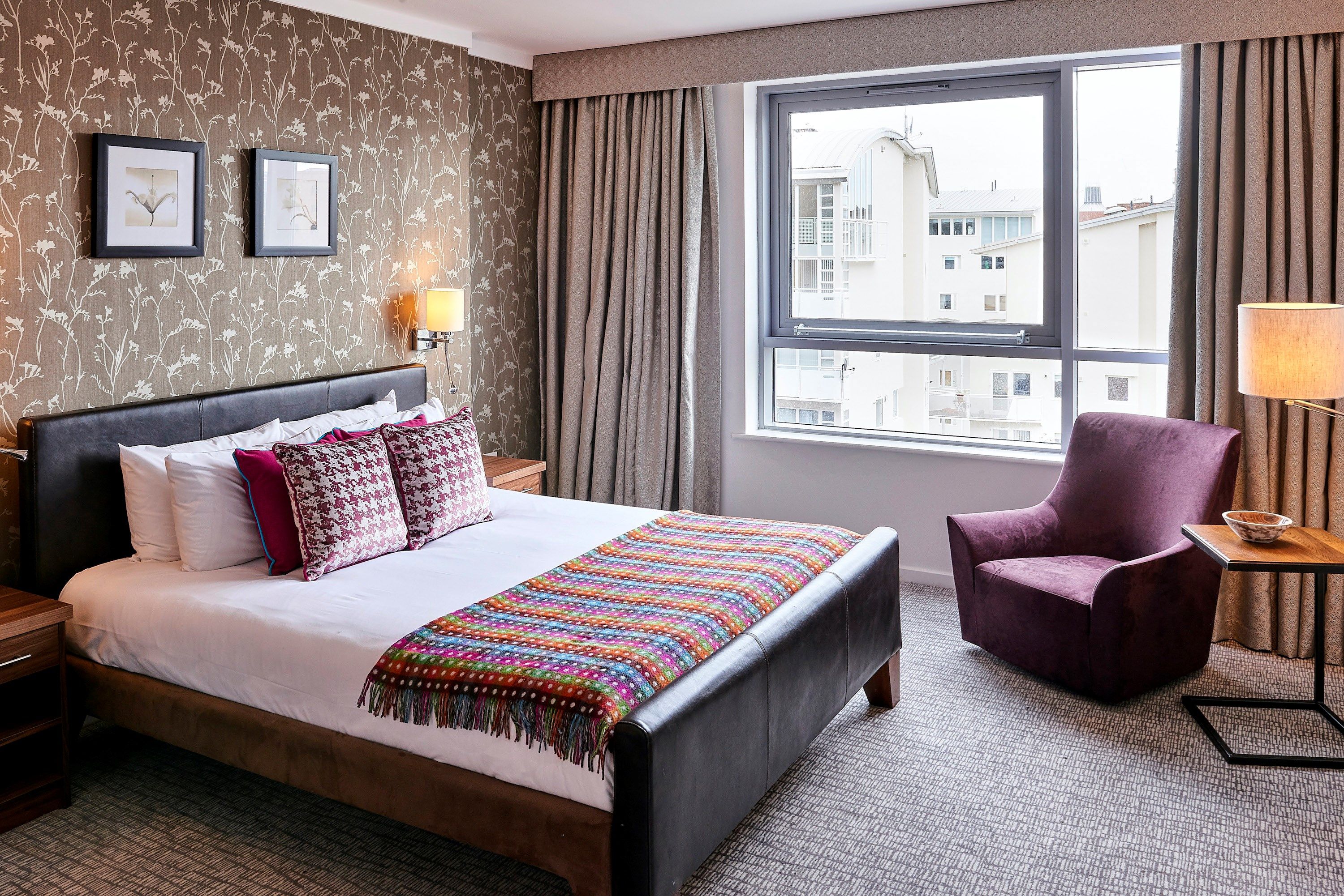 image Bright bedroom with king bed, armchair, and large windows.