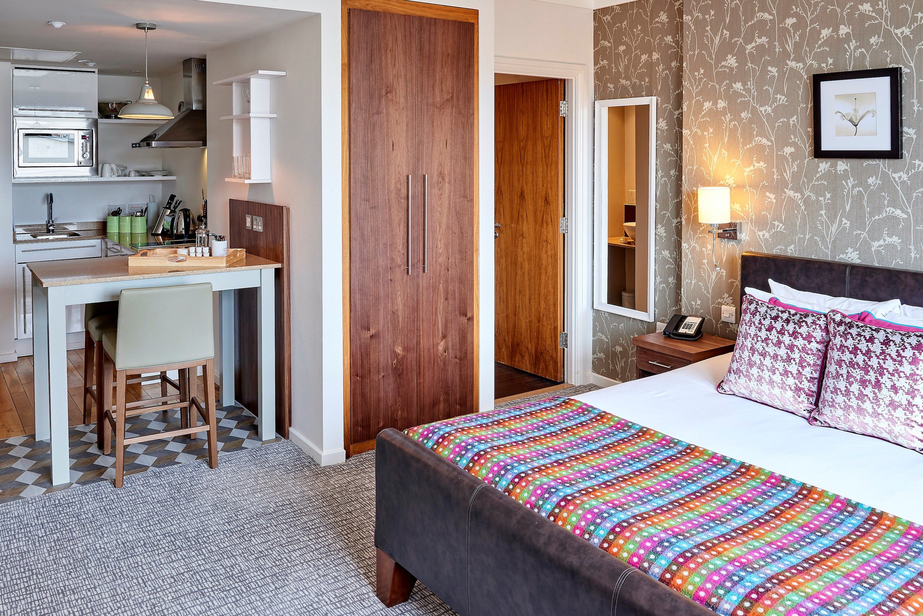 image Accessible suite featuring a cozy bed and open kitchen area.