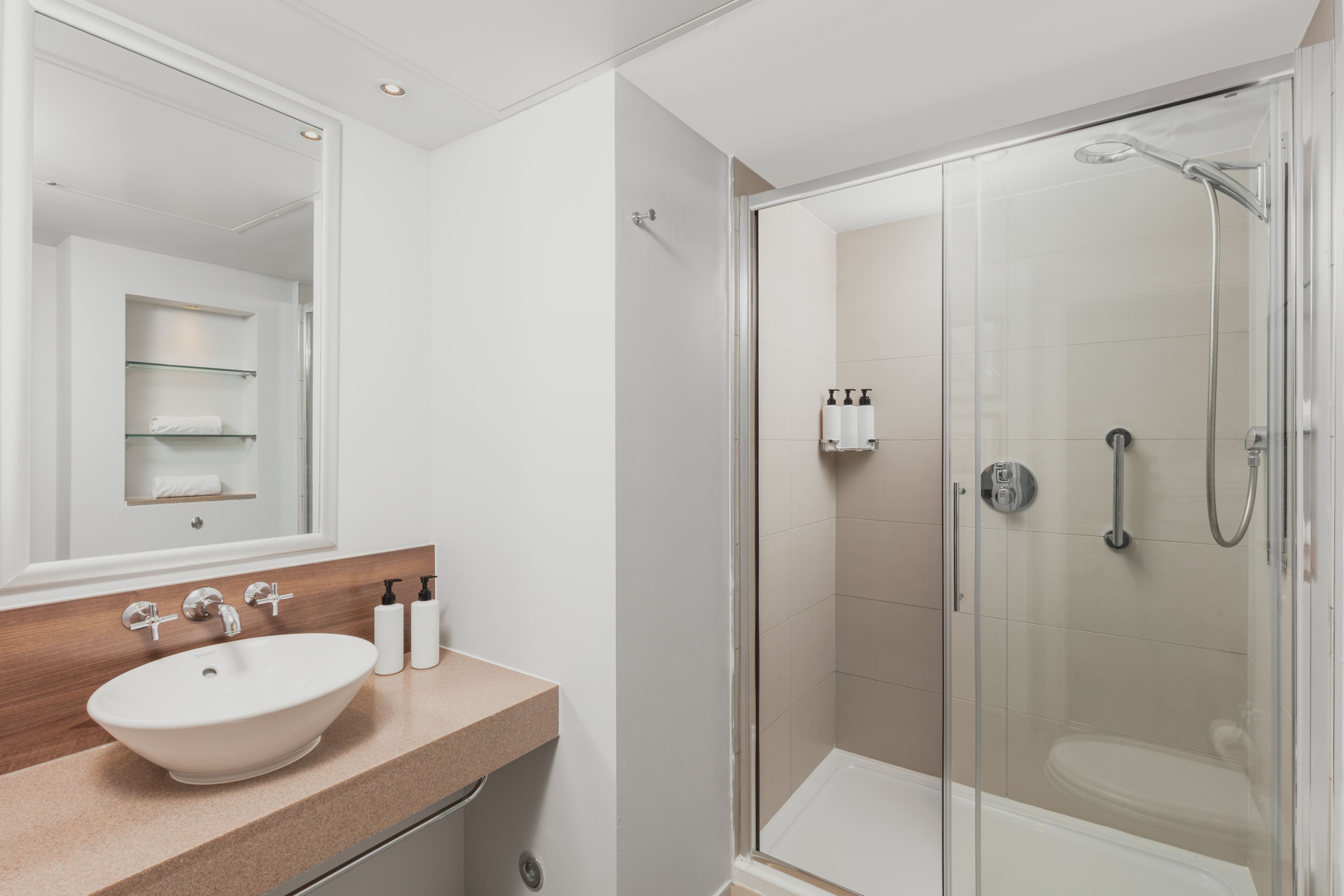 image Bathroom with walk-in shower, sink, and open shelving.