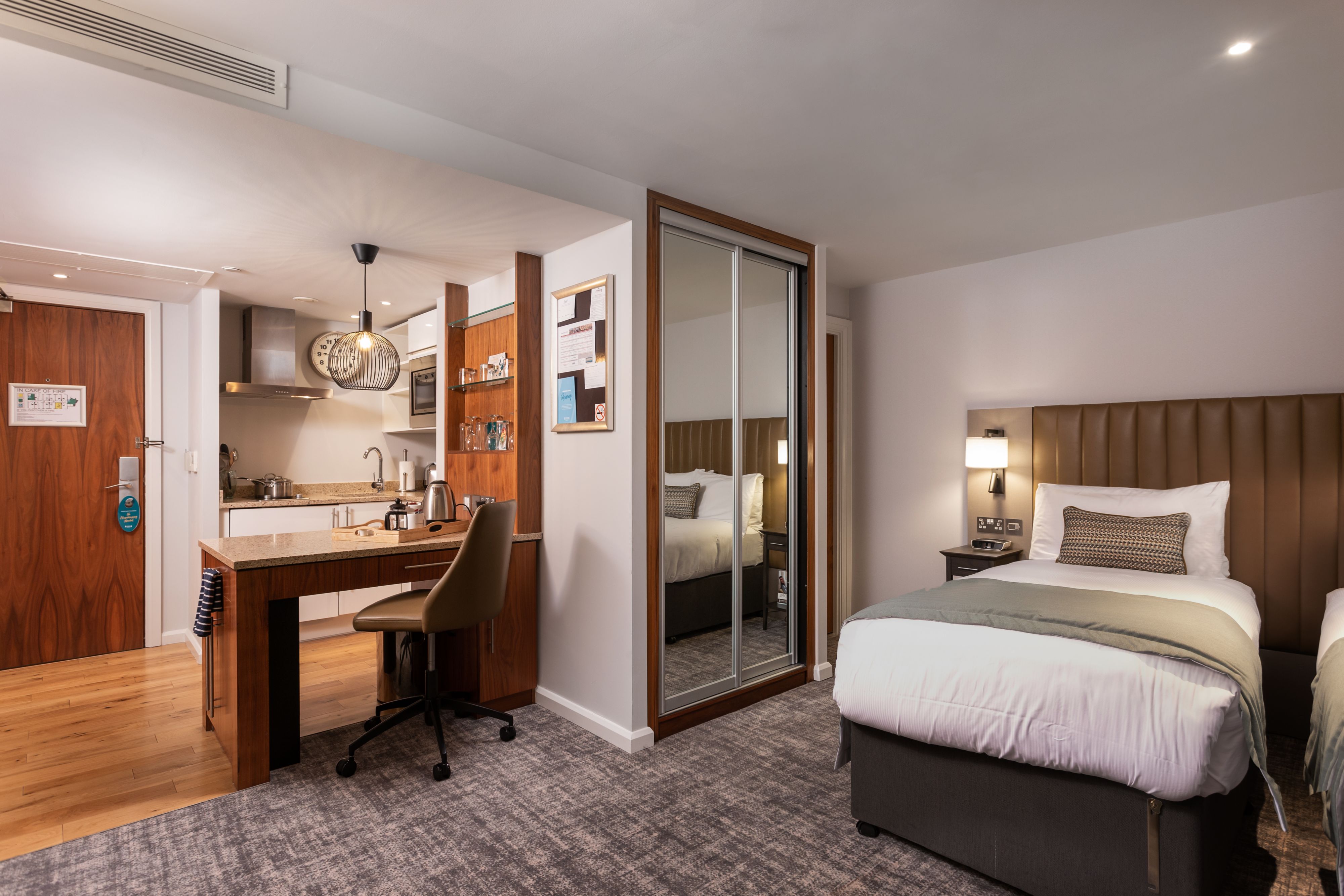image Studio room with kitchenette, bed, desk, and decorative lighting.