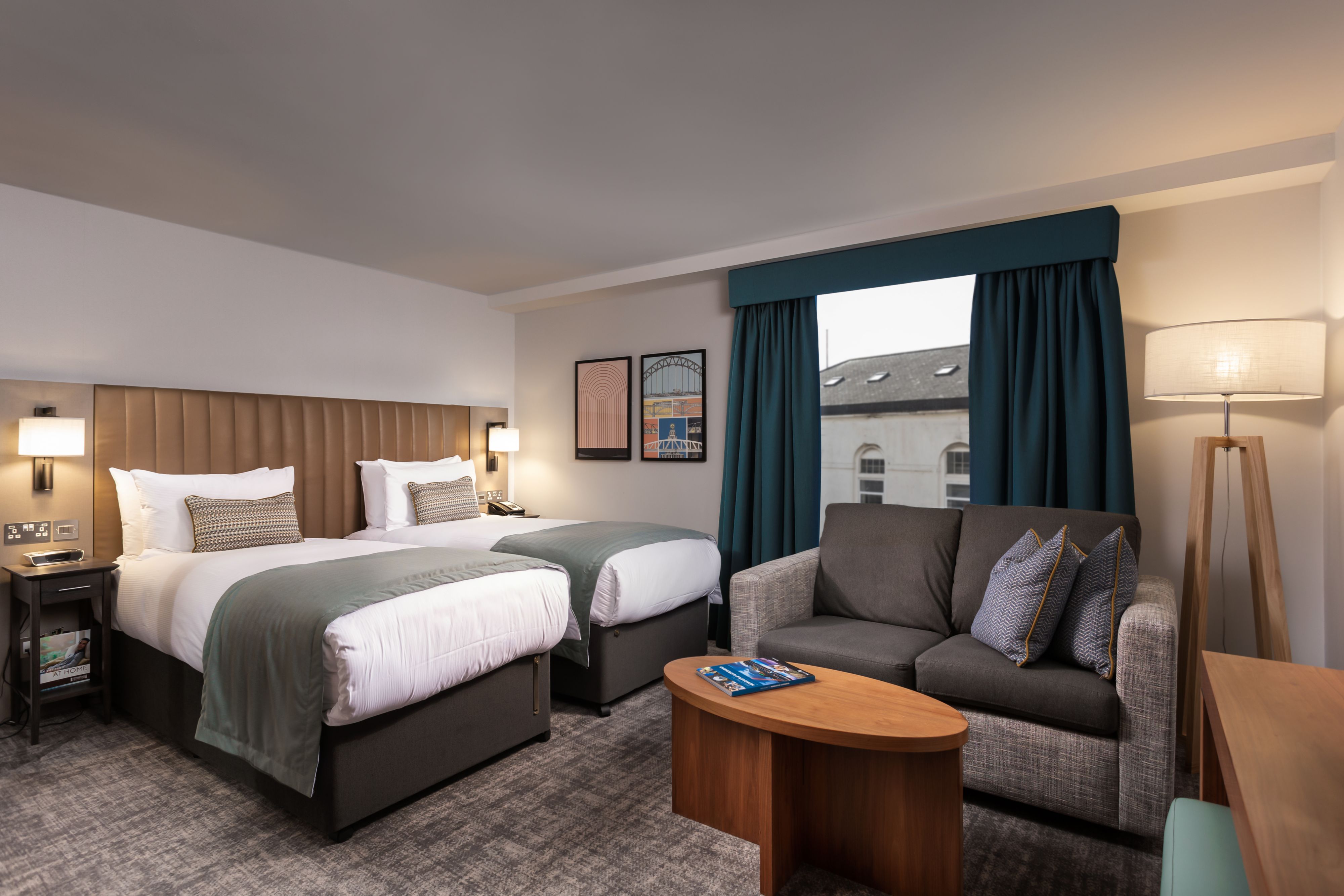 image Twin room with two single beds, seating area, and natural light.