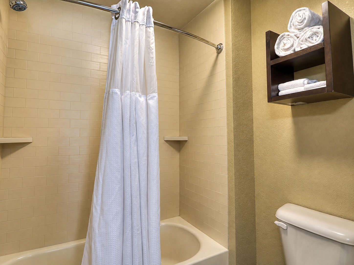 image Clean bathroom with shower and neatly arranged towels.