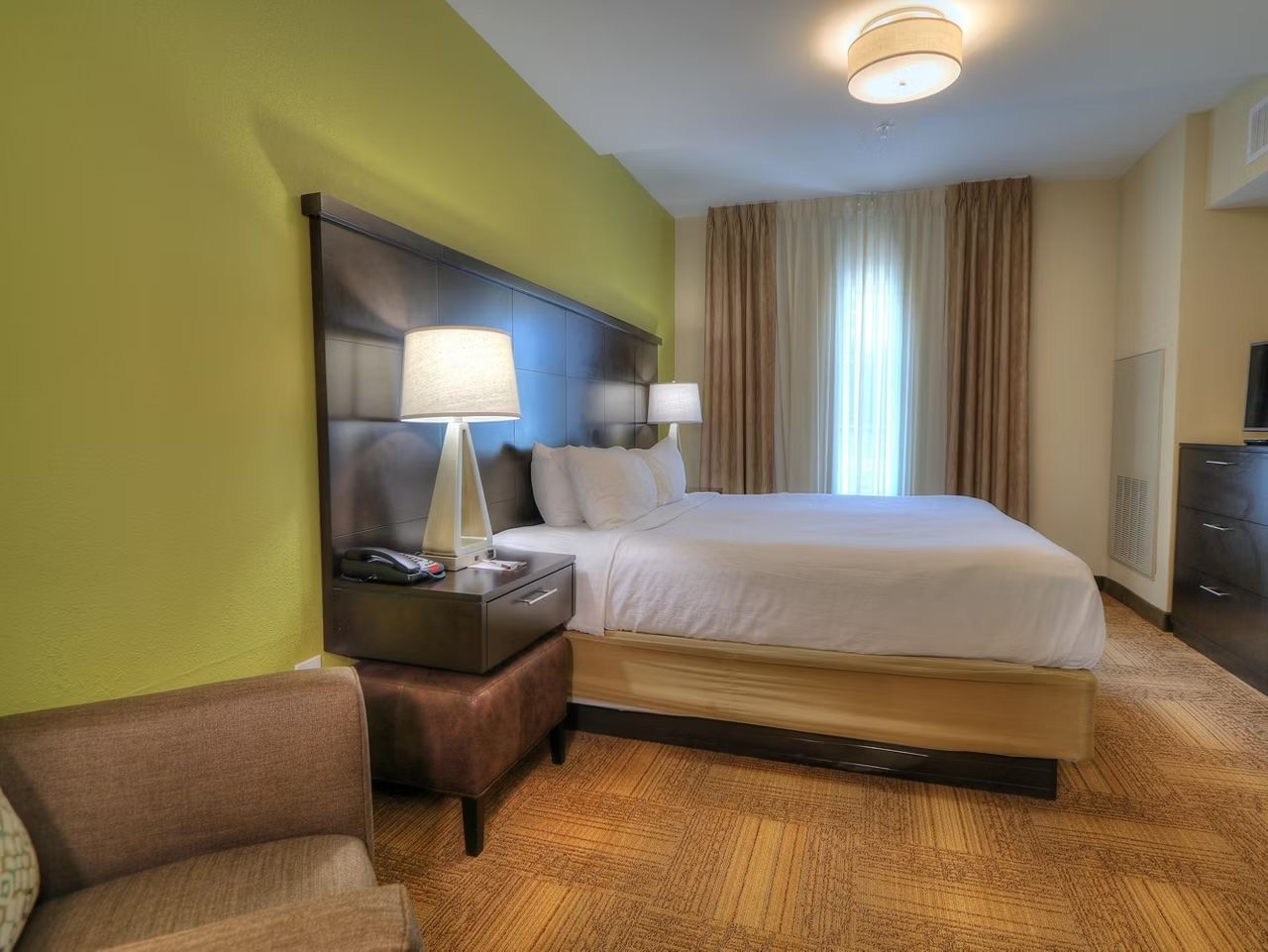 image King bedroom with flat-screen TV, dual bedside lamps, and an accessible wide-doorway layout