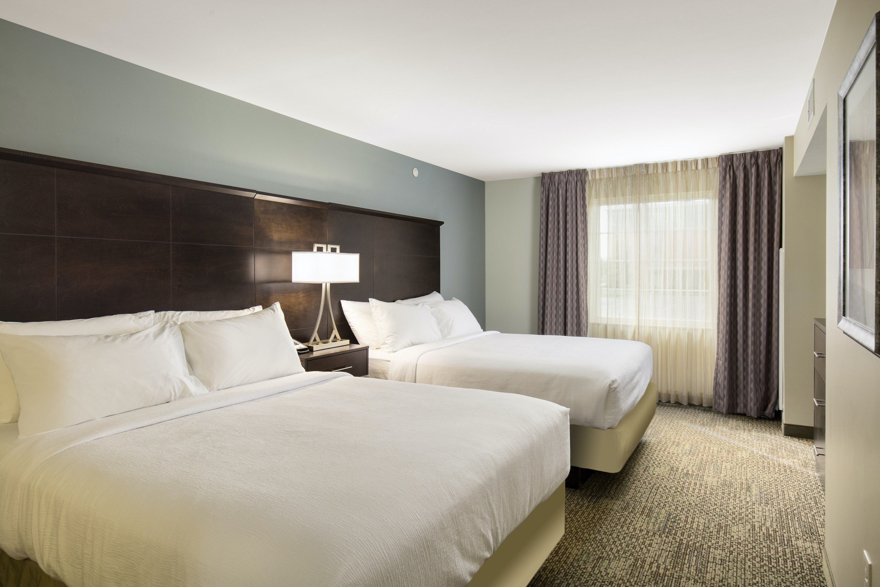 image Two double beds with white duvets face the window — blackout curtains on each side for sleeping in