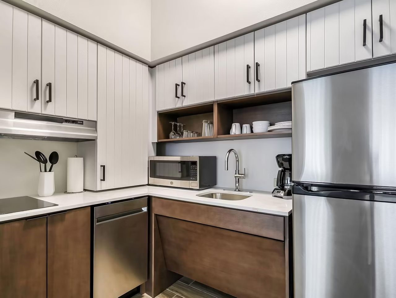 image Full kitchen with light wood cabinets, electric cooktop, stainless steel appliances, and open shelving for dishes