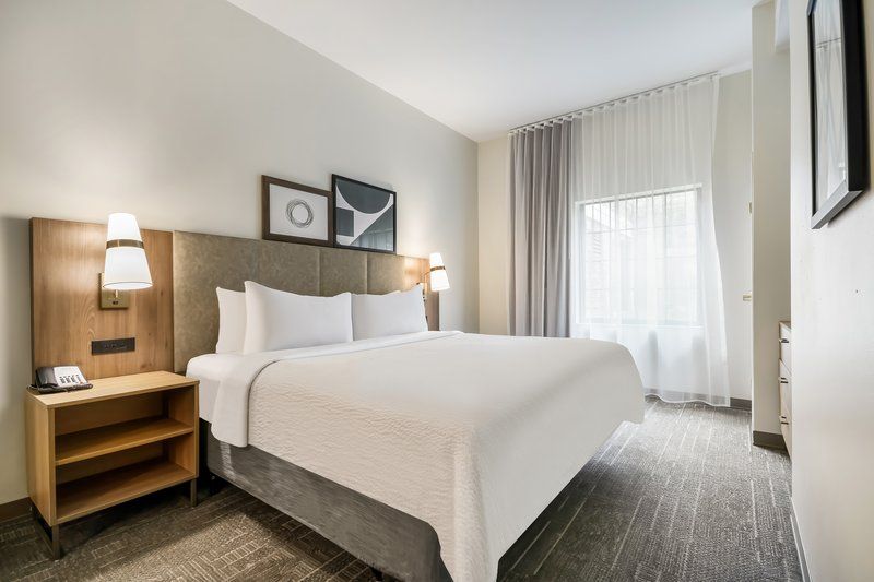 image Queen bed with white linens, bedside lamps, and wall art — bright and restful