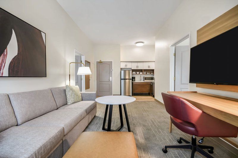 image Living area with a sofa, coffee table, and work desk — with the kitchenette visible in the background