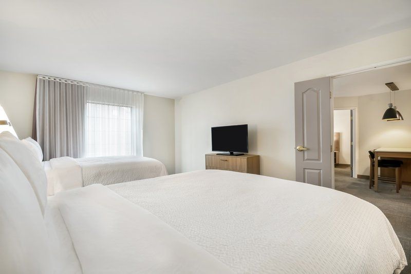 image Beds with white duvets and a wide window let morning light fill the room