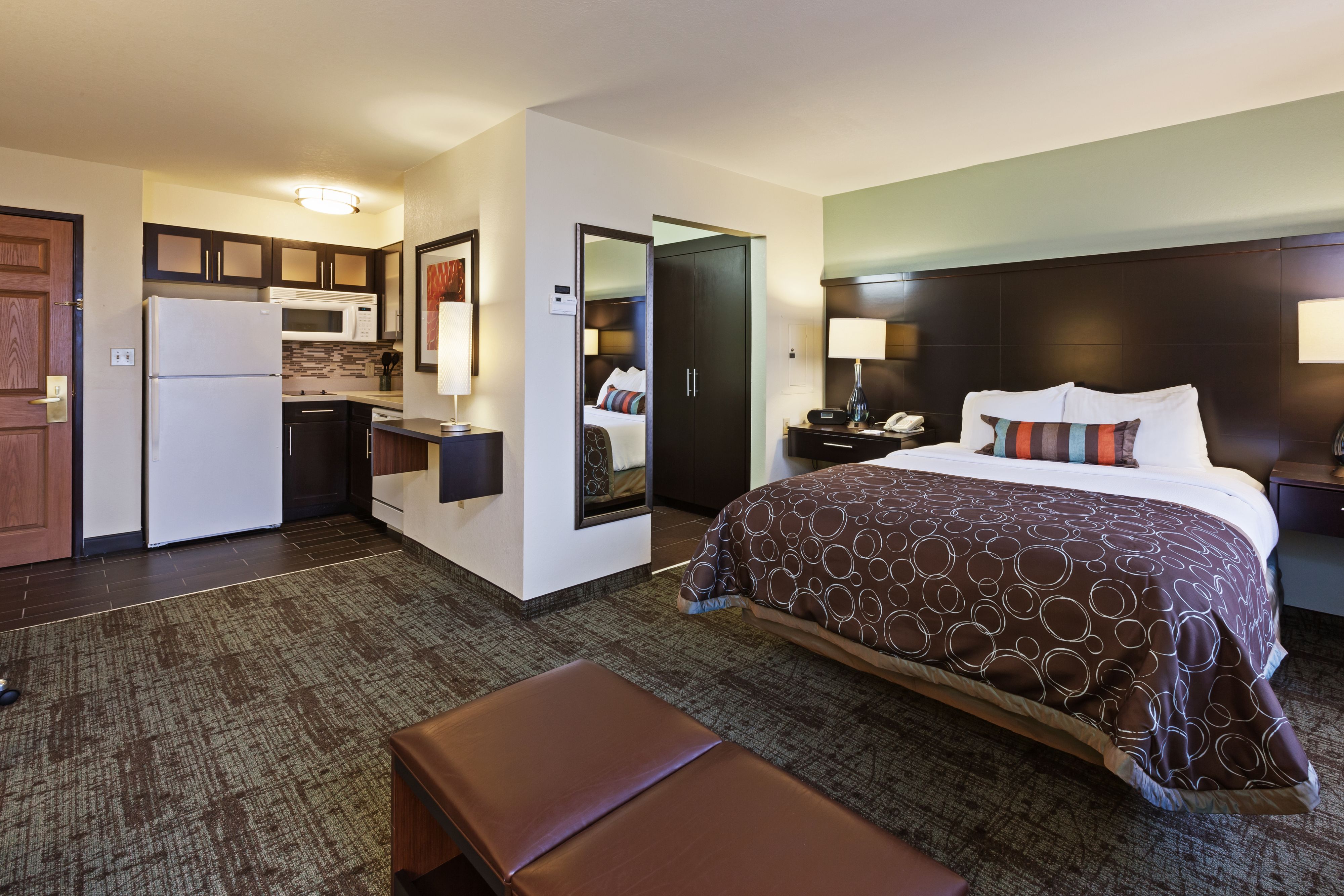 image Accessible studio bedroom with king bed, refrigerator, microwave, and lamps