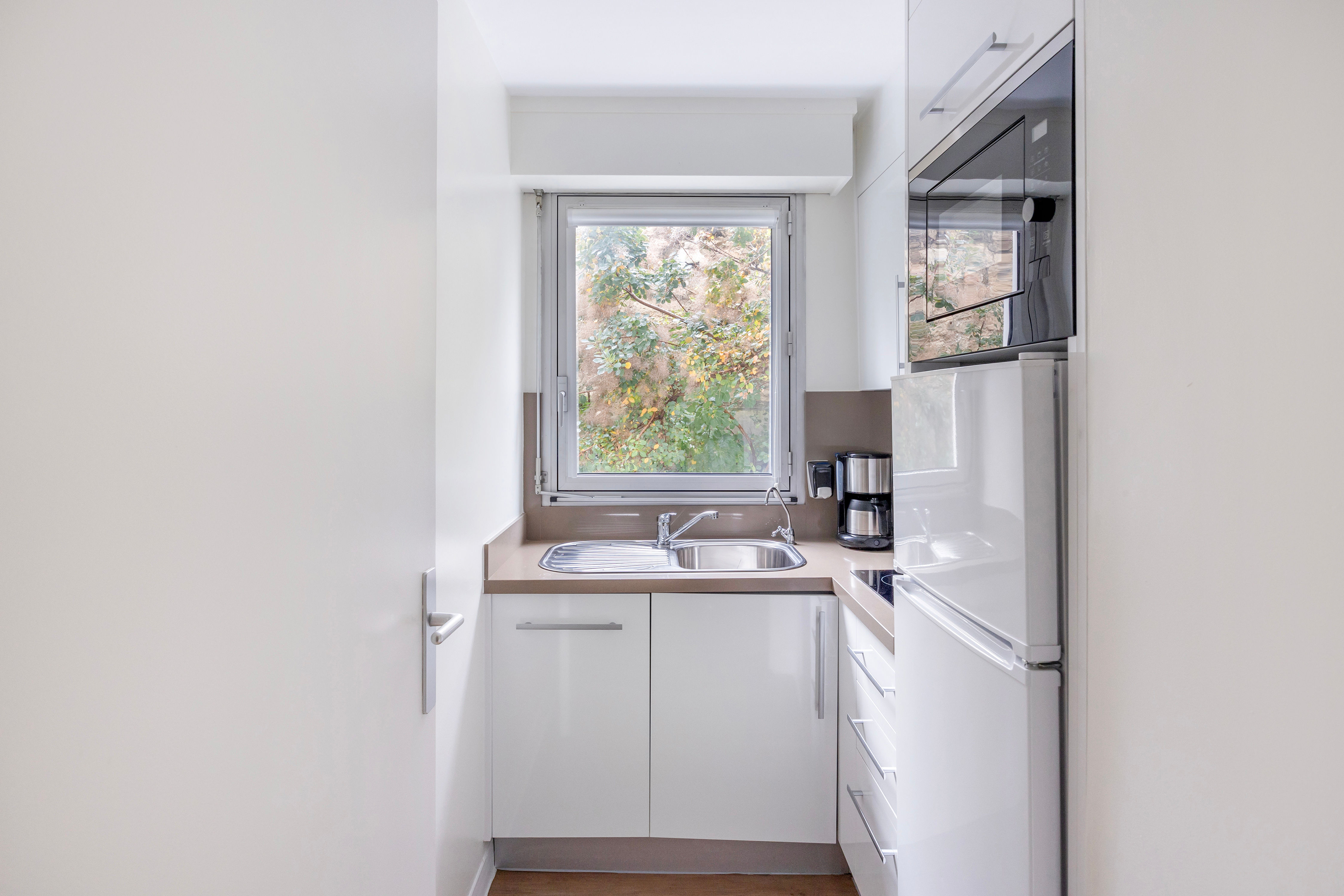 image Bright and compact kitchen equipped with hobs, a microwave, and a coffee maker, making meal prep a breeze.