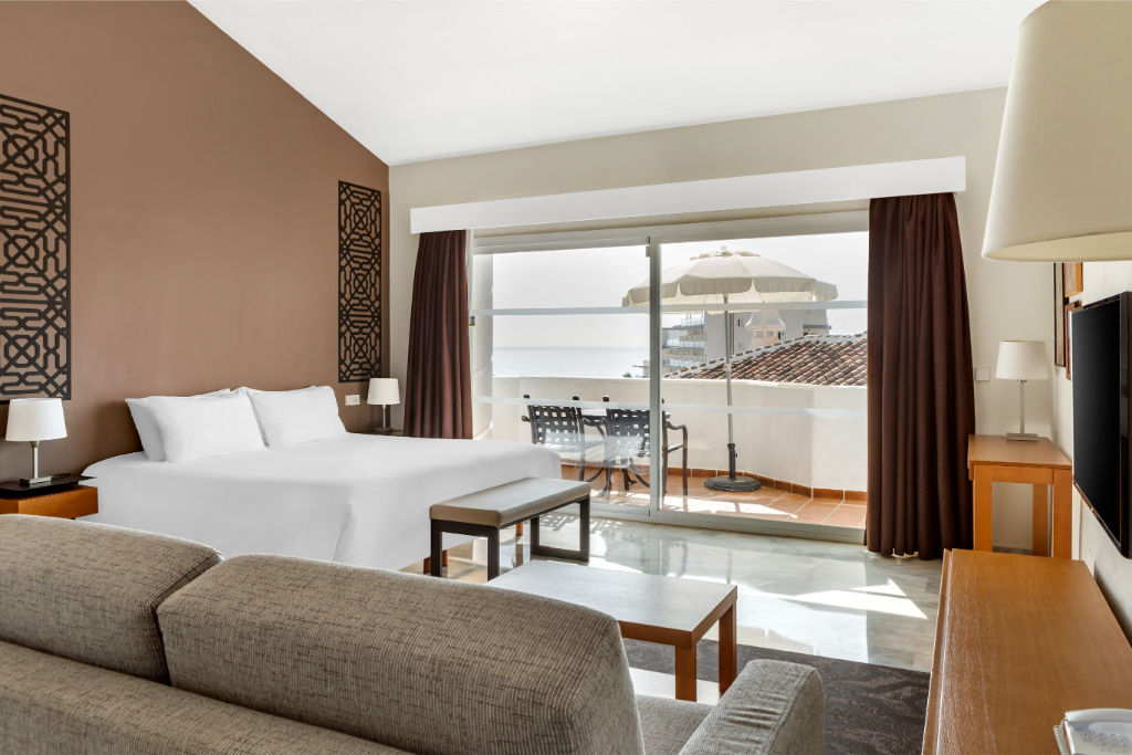 image Luxuriously appointed suite with expansive windows, offering panoramic views and a plush seating area.