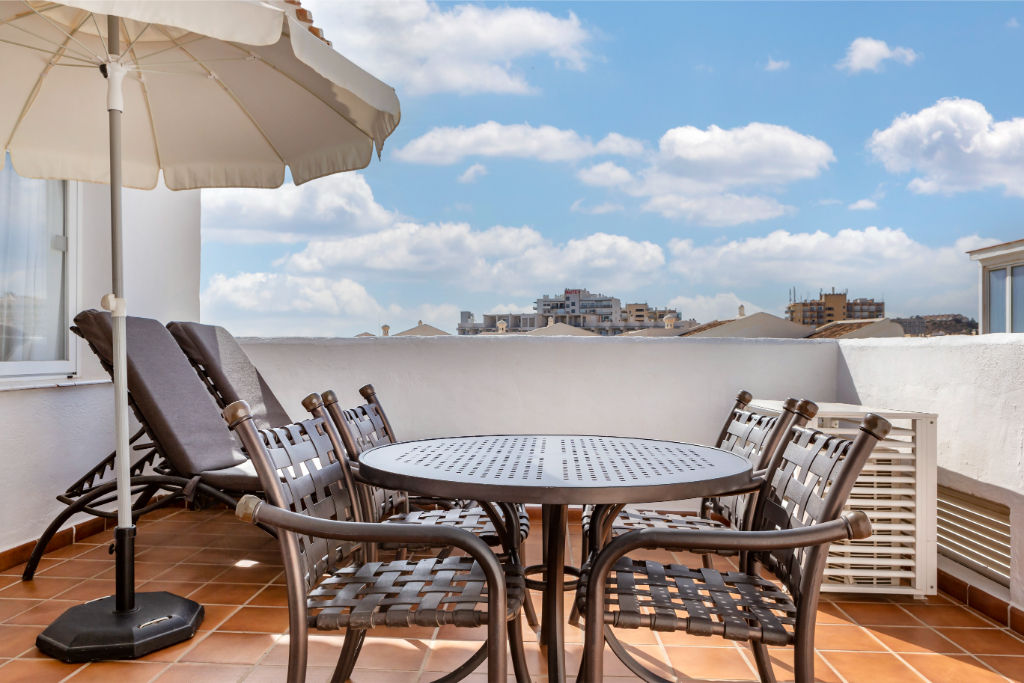 image Spacious rooftop terrace with dining set under an umbrella, ideal for al fresco meals with a view.