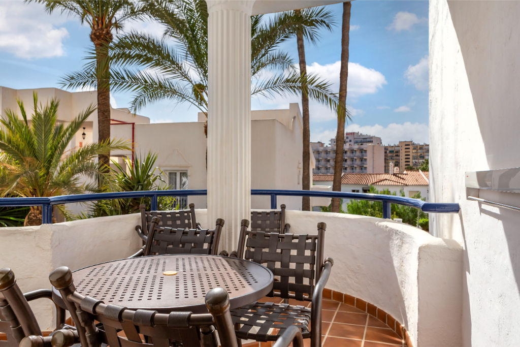 image Covered balcony with comfortable seating, offering a private outdoor space to dine and relax.