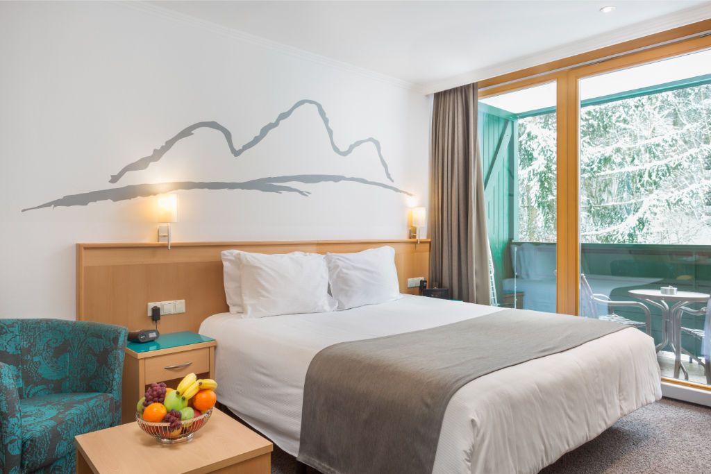 image A bedroom oasis with plush bedding and serene mountain art.