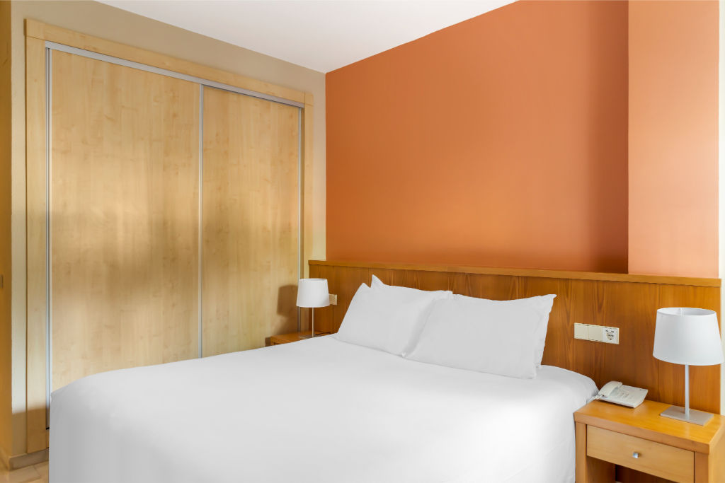 image A bedroom with a warm glow, providing a comfortable and minimalist space for a restful night's sleep.