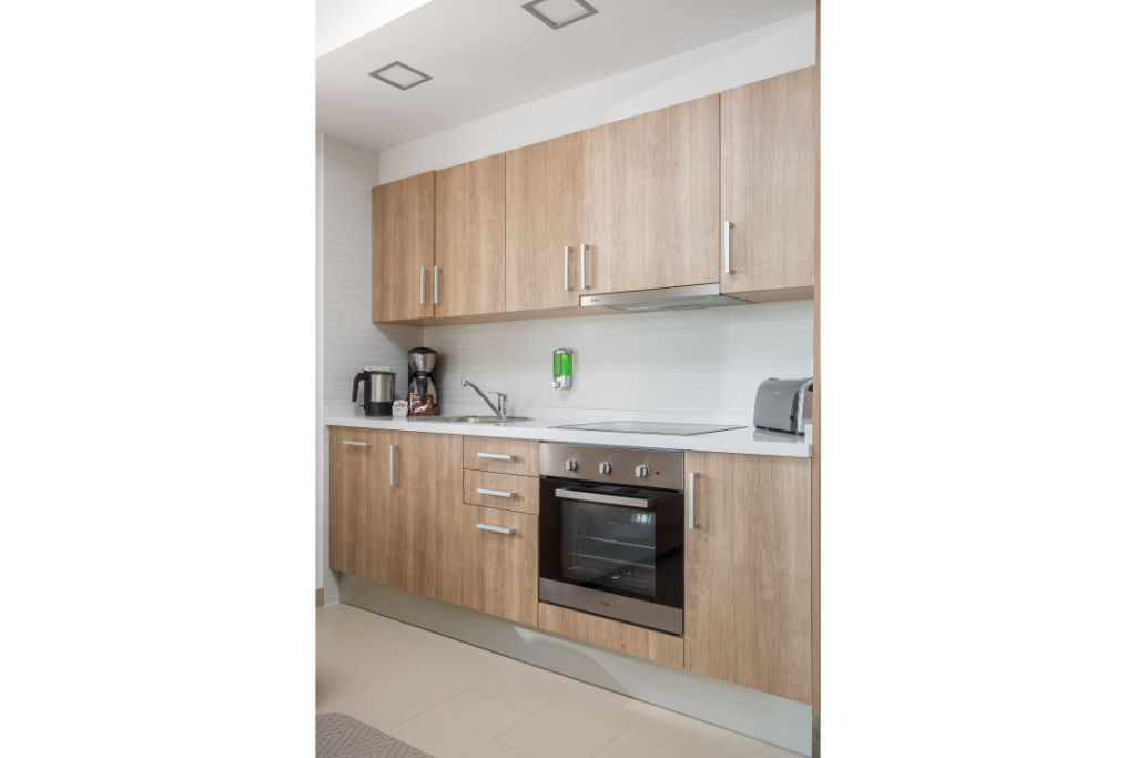 image Compact, fully equipped kitchen with wooden cabinetry and modern appliances.
