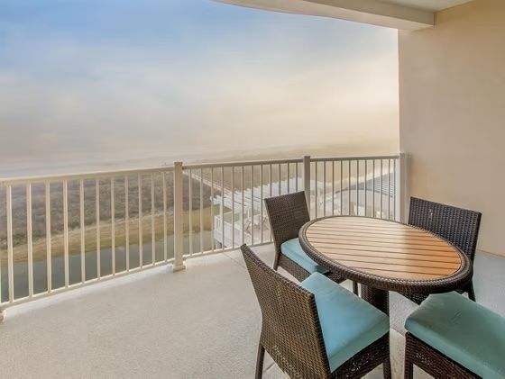 image Private balcony with round wood table and rattan chairs — morning coffee with treetop views