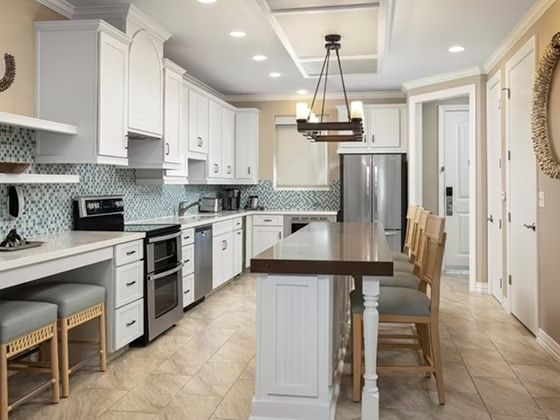 image Light-filled kitchen with blue tile backsplash, stainless appliances, and plenty of prep space