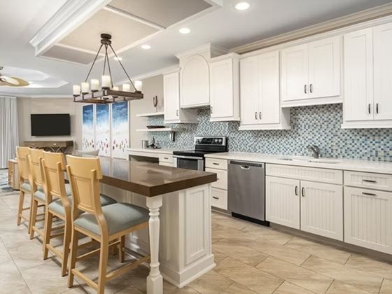 image White kitchen with mosaic tile backsplash, large island, and full stainless steel appliance suite