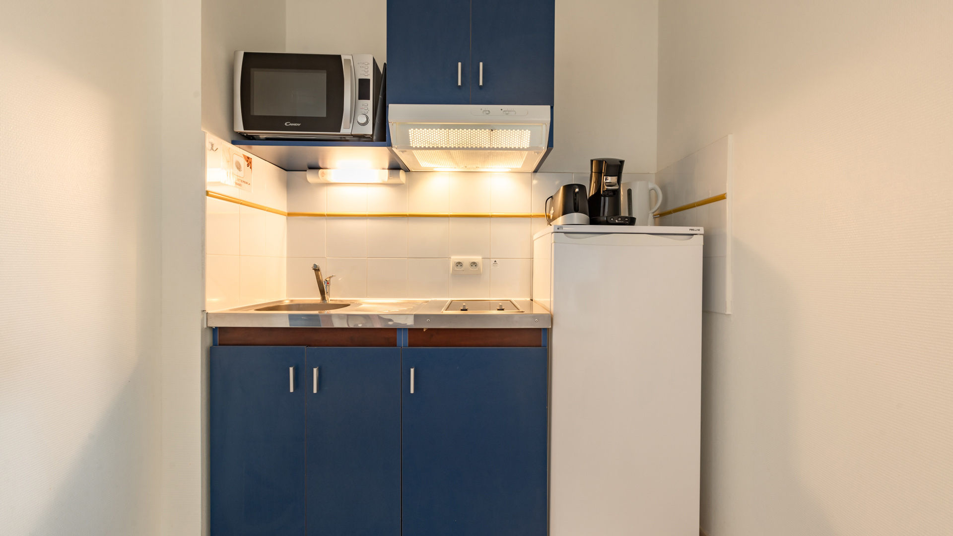 image A fully equipped kitchenette featuring all the essentials, including a microwave, fridge, and stovetop.