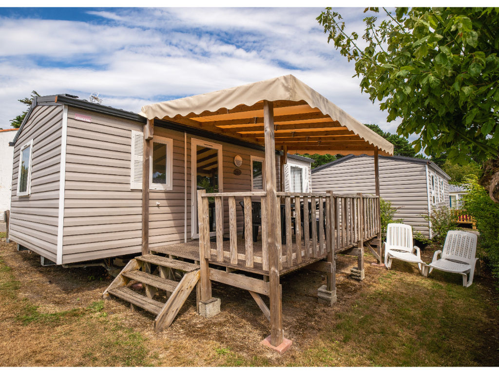 image A charming mobile home with a shaded deck, perfect for relaxing in nature’s tranquility.