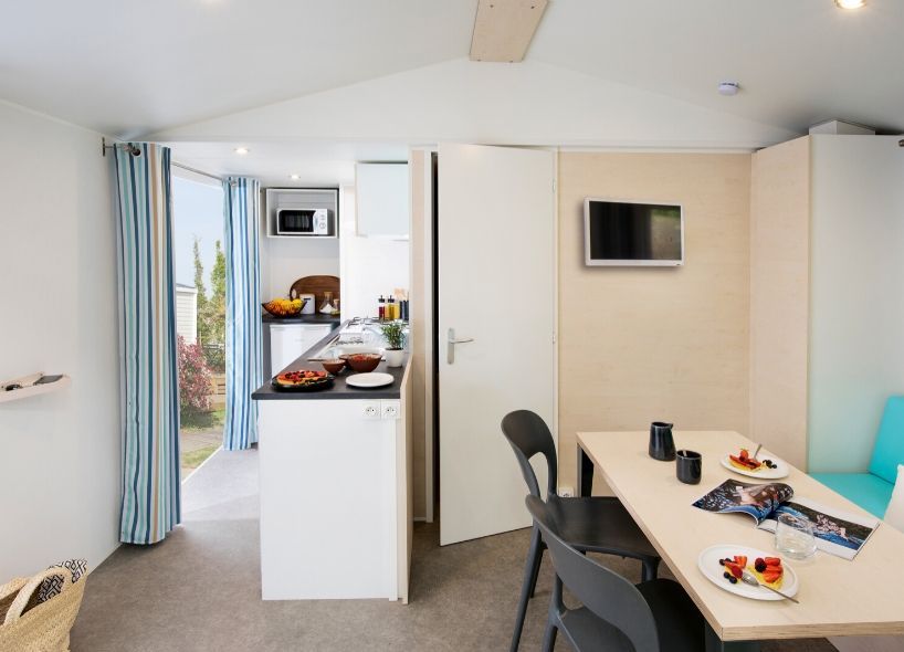 image The modern mobile home blends seamlessly into its natural surroundings, offering both comfort and a welcoming seaside atmosphere.