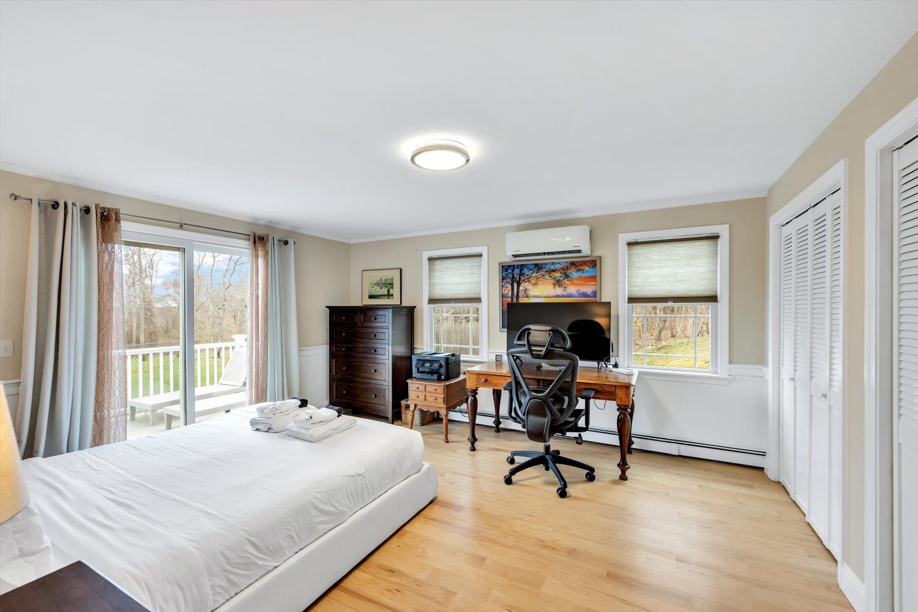image Bedroom with king bed, white linens, chest of drawers, desk with computer, and glass door to balcony